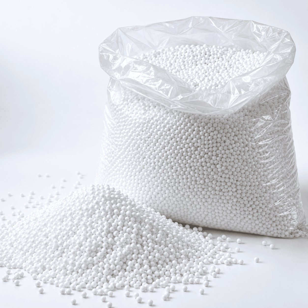 White polystyrene filling beads in an open clear sack, with loose beads alongside